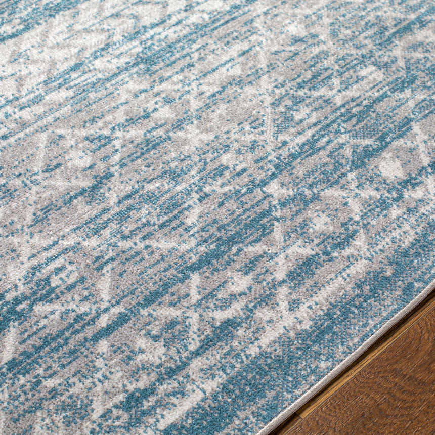 Close-up of the Tambac Blue Washable Area Rug showing its distressed gray and blue pattern and soft texture. Texture