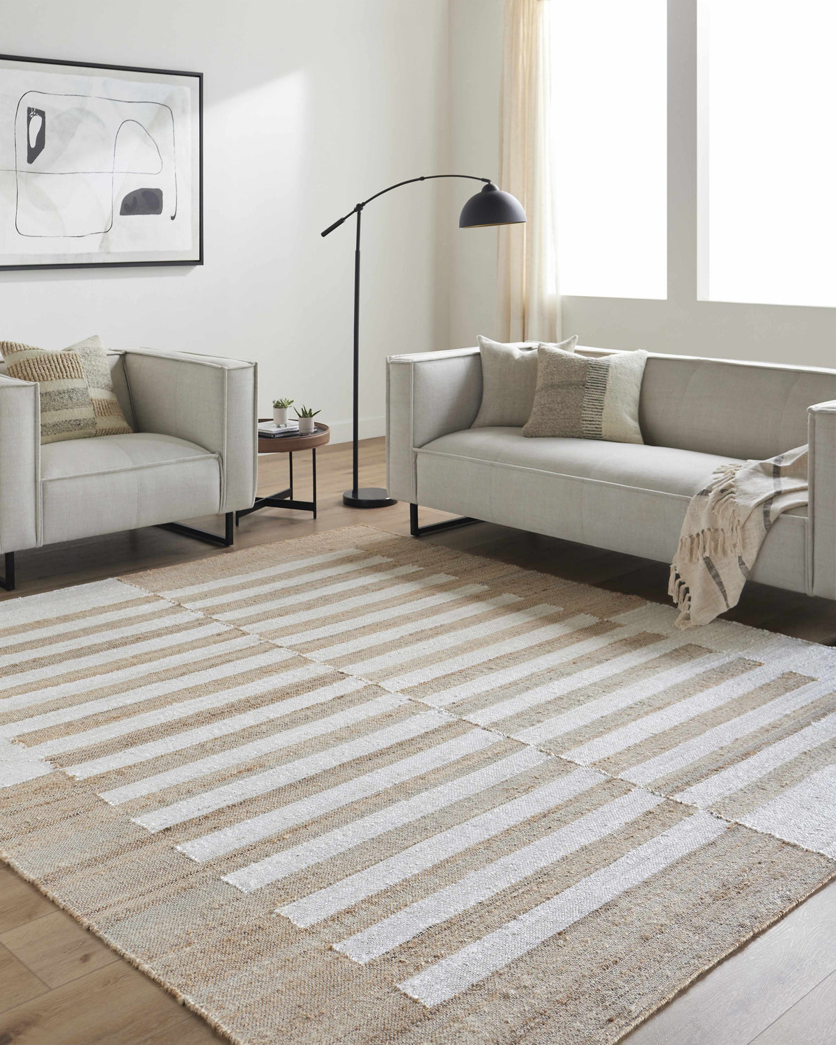 Living room with a neutral sofa and the striped Soren Area Rug in ash, light silver, and tan. Roomscene-Rectangle