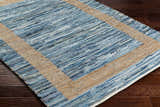 Close-up of the Ghita Recycled Blue Jean Rug showing its hand woven texture, blue denim stripes, and beige border. Corner