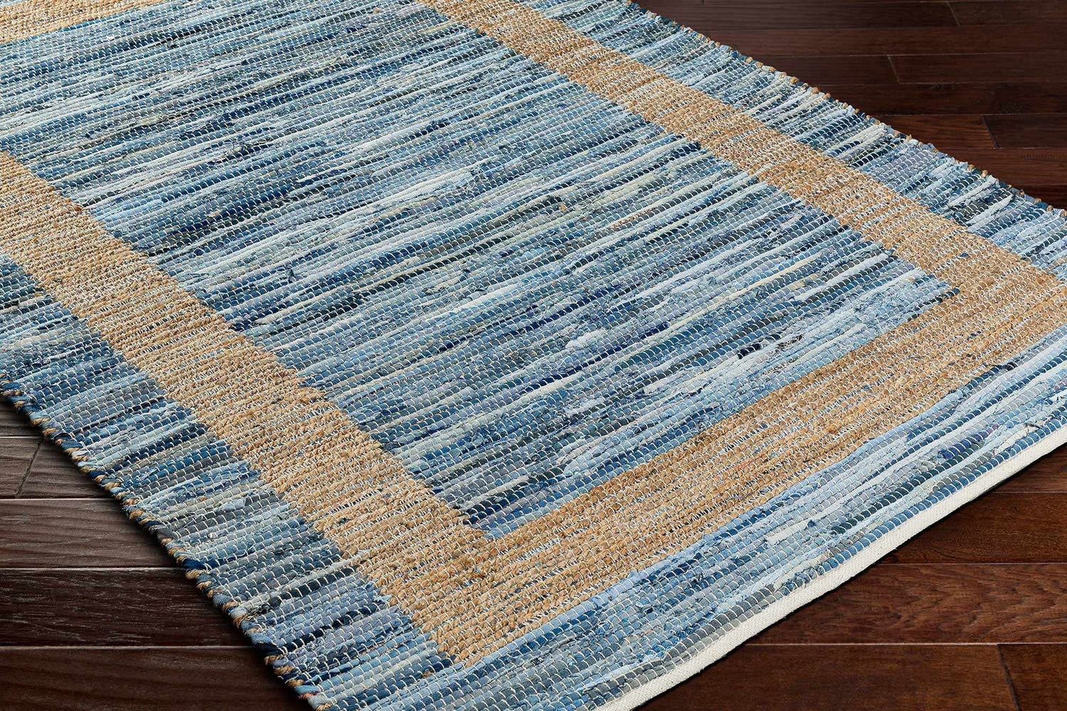 Close-up of the Ghita Recycled Blue Jean Rug showing its hand woven texture, blue denim stripes, and beige border. Corner