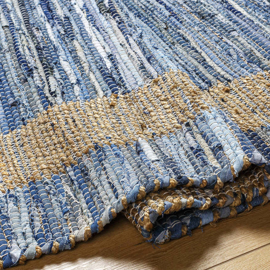 Close-up of the hand woven Ghita Recycled Blue Jean Rug, showing denim blue and beige jute textures. Contemporary style. Fold