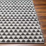 Close-up of the hand woven Gzifa Jute Rug. The rug has a contemporary black and beige geometric pattern. Front