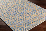 Close-up of the hand woven Isaye Blue Area Rug. Features a contemporary blue and brown geometric pattern. Corner