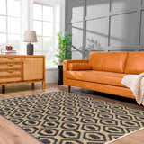 Living room scene with an orange sofa and the Isaye Charcoal Area Rug featuring a black and beige geometric pattern. Roomscene-Rectangle