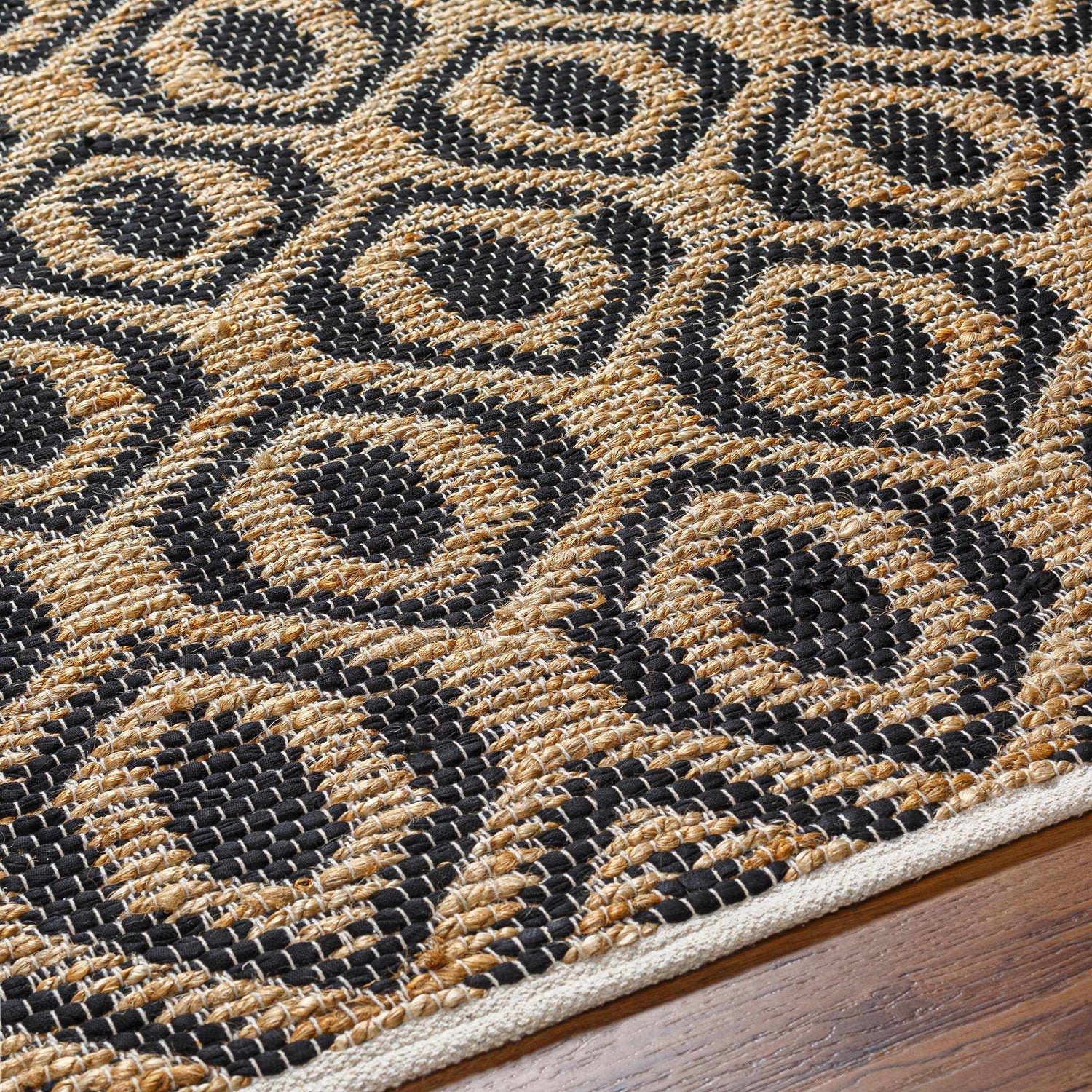Close-up of the hand-woven Isaye Charcoal Area Rug, featuring a geometric pattern in jute and black recycled fabric. Texture