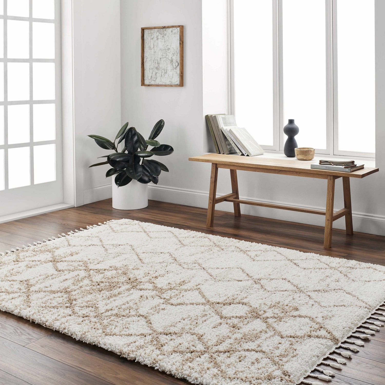 Bright living room with Ishan Cream Area Rug, wood floors, bench with books, and potted plant. Roomscene-Rectangle
