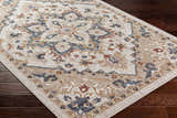 Close-up of Lewa Cream Area Rug on dark wood floor. Traditional, farmhouse style rug with blue, taupe, and burgundy pattern. Corner