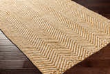 Close-up of the Aren Area Rug showing a geometric chevron pattern in natural jute and light beige colors. Corner