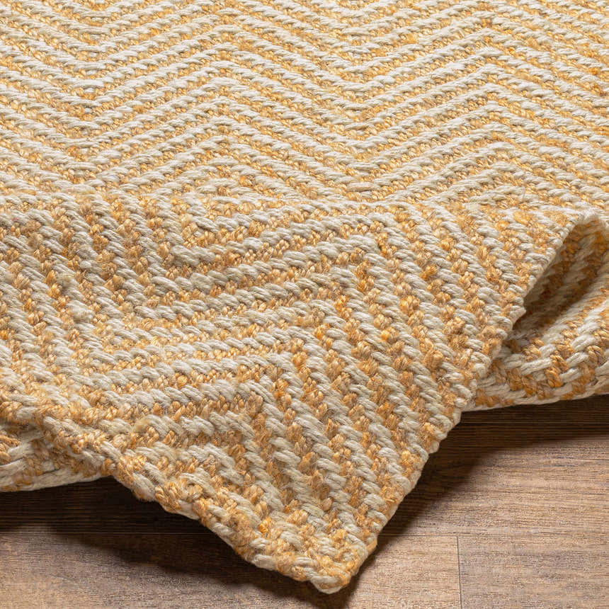 Close-up of the Aren Area Rug showing the cinnamon and light beige jute woven geometric pattern. Fold