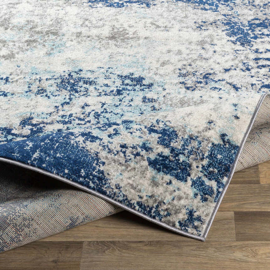 Close-up of the Slamannan Area Rug showing its aqua, charcoal, dark blue, gray, and off-white contemporary design. Fold