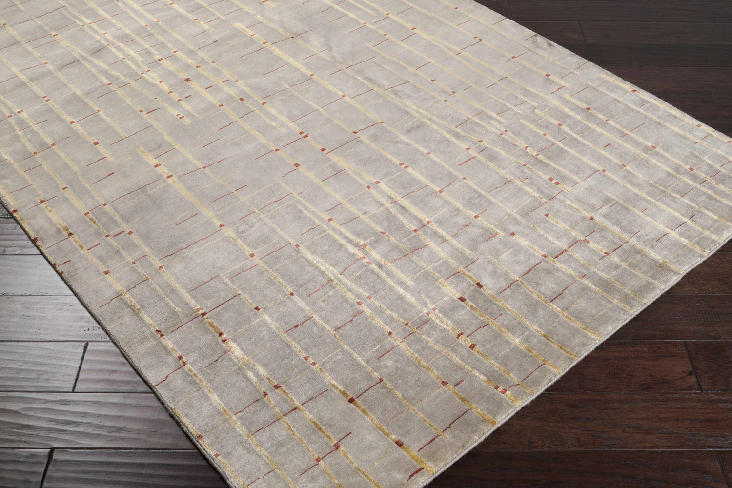 Close-up of the Slatington Area Carpet showing a gray wool rug with a gold and red geometric line pattern. Corner