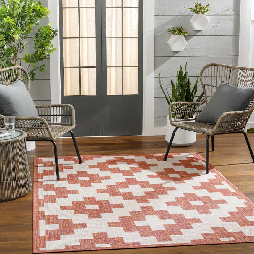 Patio scene with Arwa Area Carpet in coral and white, wicker chairs, and wood flooring. Roomscene-Rectangle