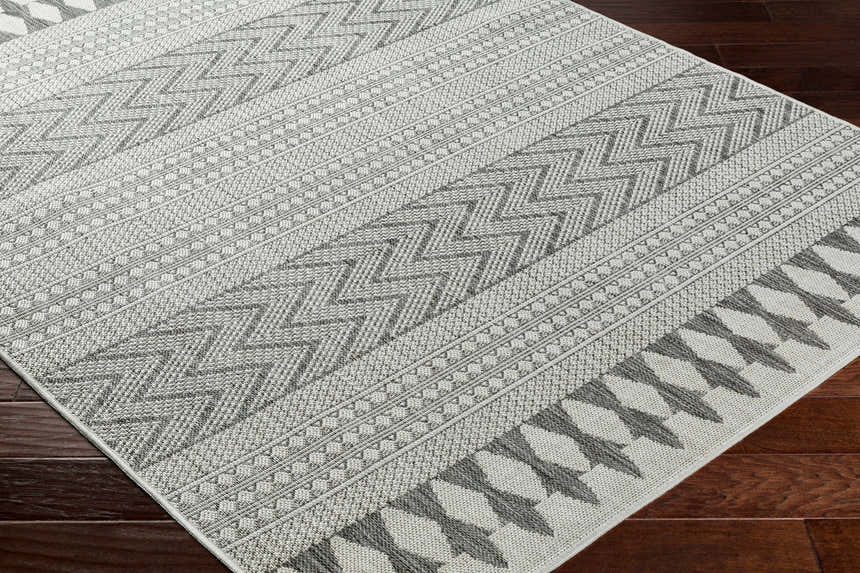 Close-up of the Asif Gray Area Rug showing the farmhouse style geometric pattern and woven texture on dark wood floors. Corner