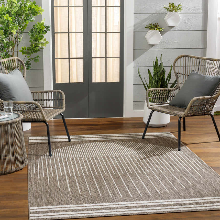 Outdoor patio scene with the Aviya Brown Area Rug, wicker chairs, and wood flooring. Roomscene-Rectangle