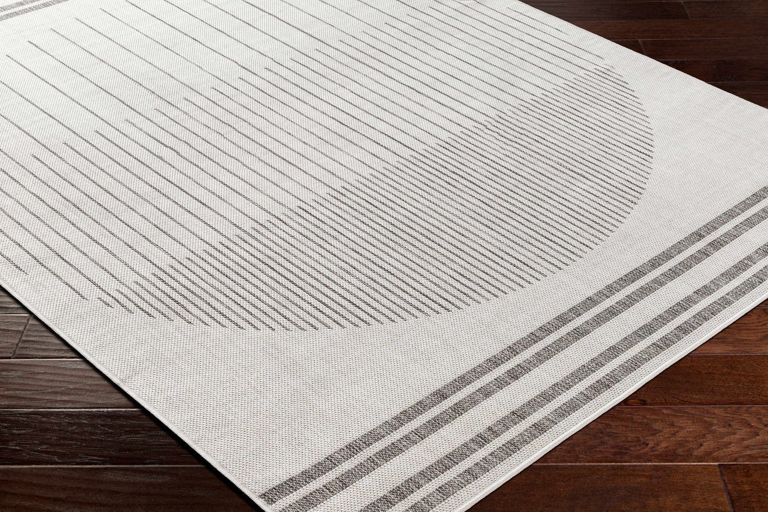 Close-up of Aviya Light Gray Area Rug showing a geometric pattern of gray lines and stripes on an off-white background. Corner