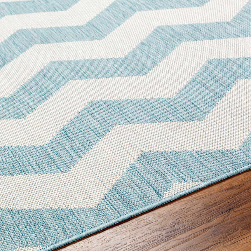 Close-up of Cheri Thatch Light Blue Area Carpet. Chevron pattern in light blue and white. Machine woven texture detail. Texture
