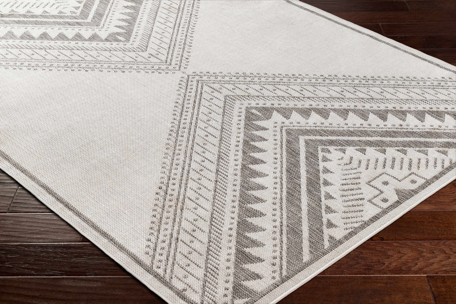 Close up of the Deana Light Gray Area Rug showing its geometric, tribal-inspired pattern and woven texture. Corner