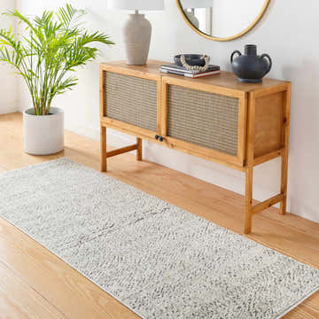 Entryway with wood floors and a bone-colored Truc Area Rug runner, console table, plant, and round mirror. Roomscene-Runner