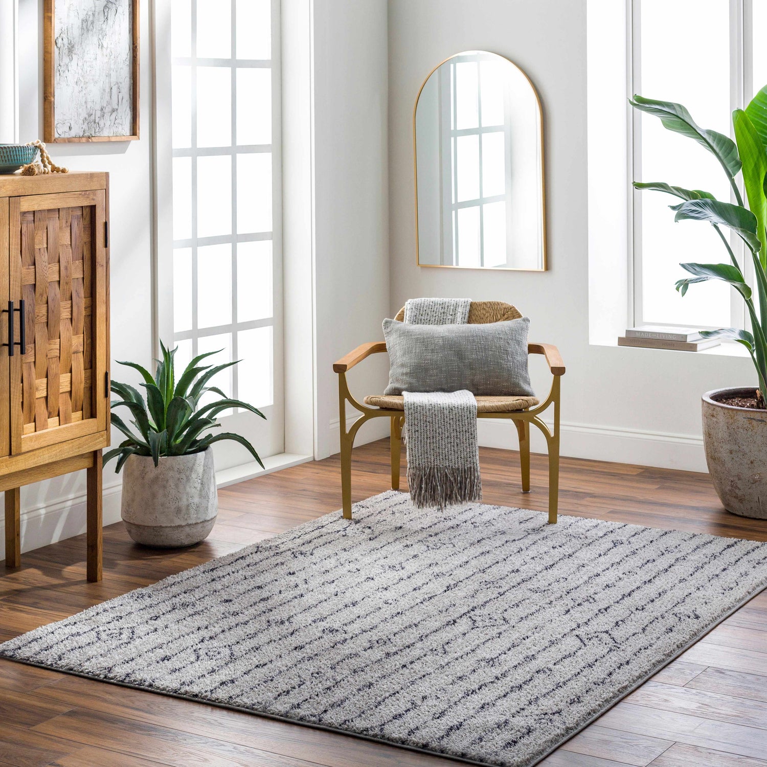 Light-filled room with a Demi Gray Washable Area Rug, wood cabinet, chair with throw, and potted plants. Farmhouse style. Roomscene-Rectangle