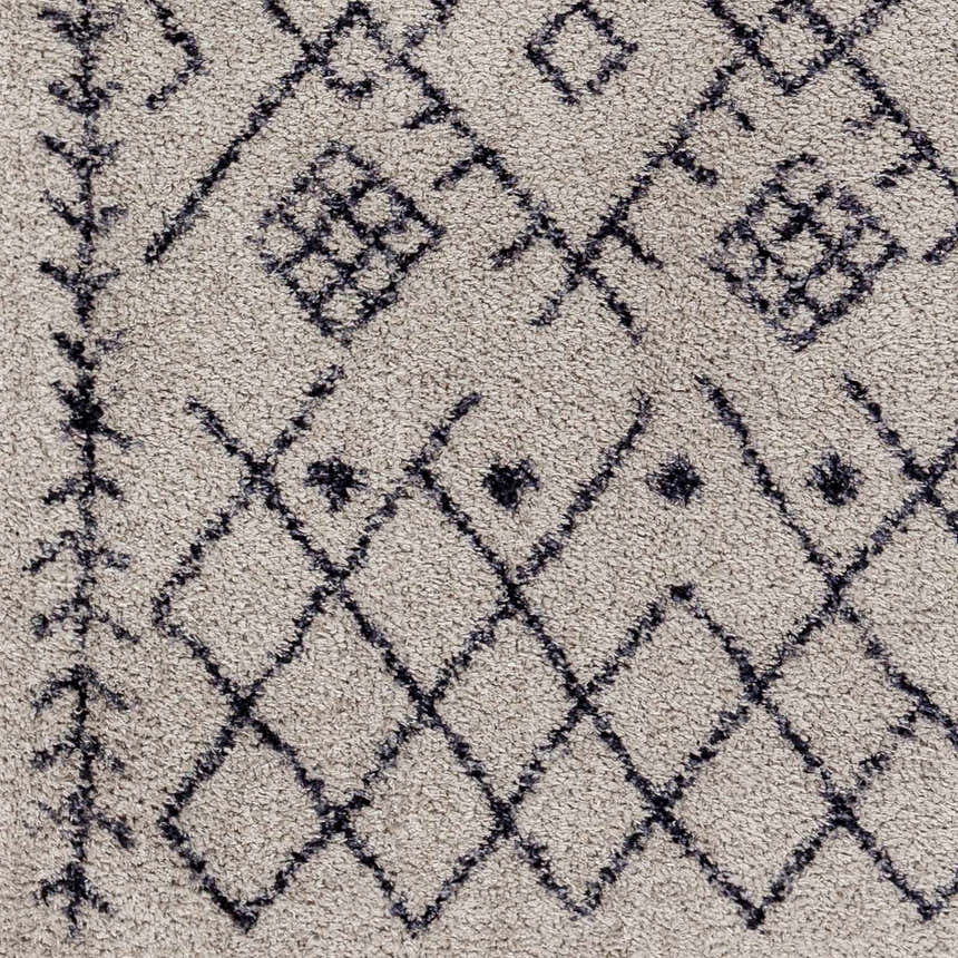 Close-up of the Elyes Gray Washable Area Rug. Features a shag texture with a dark gray diamond and geometric pattern. Swatch