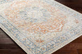 Close-up of the Emke Rust Washable Area Rug showing its faded driftwood, nutmeg, and dark beige traditional pattern. Corner