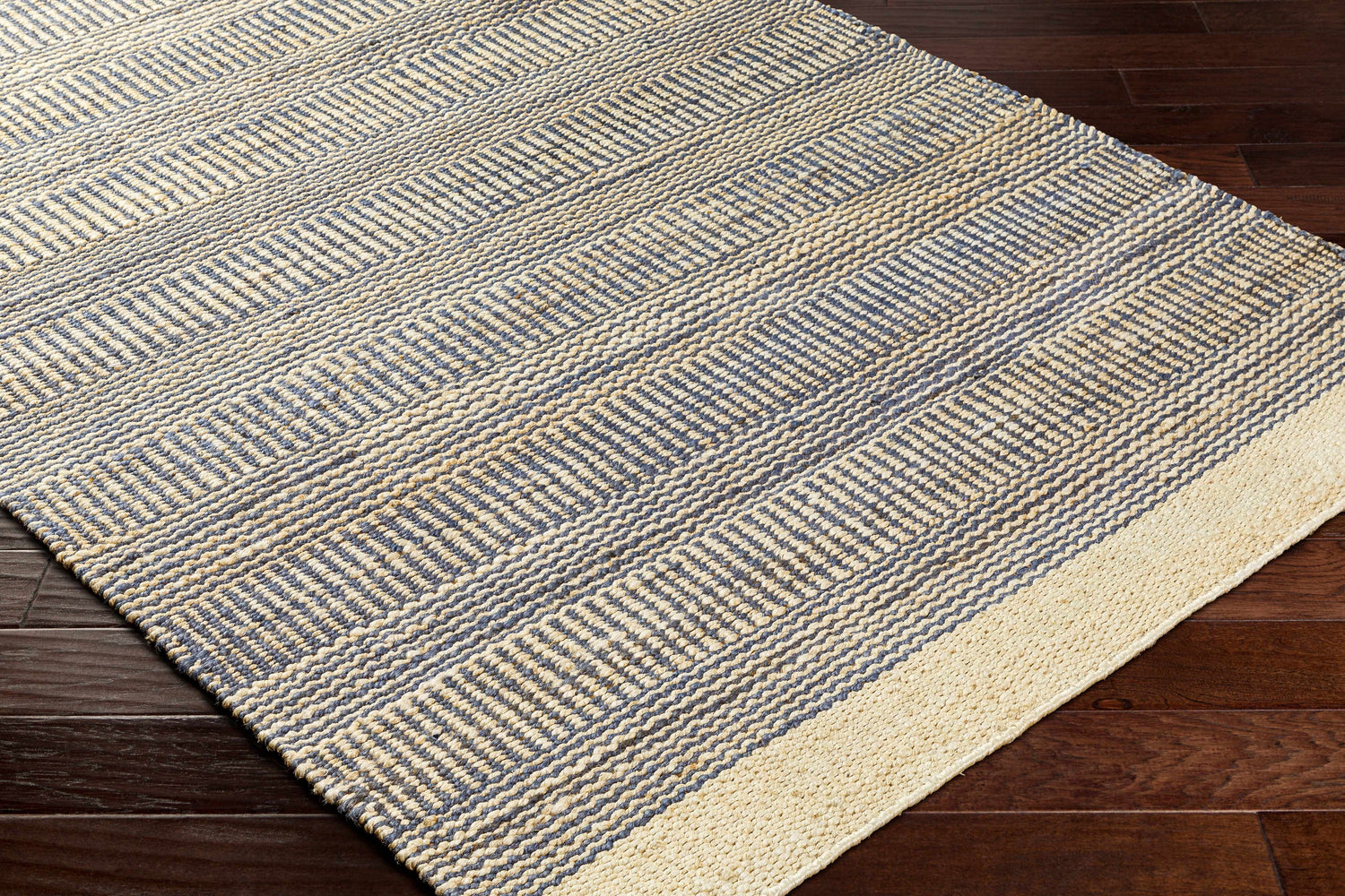 Close-up of the hand woven Blue Elle Area Rug. Jute rug with charcoal and natural geometric pattern. Corner