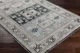 Close-up of the Sultanbeyli Area Carpet, a traditional rug in black, cream, gray, and teal, on dark wood flooring. Corner