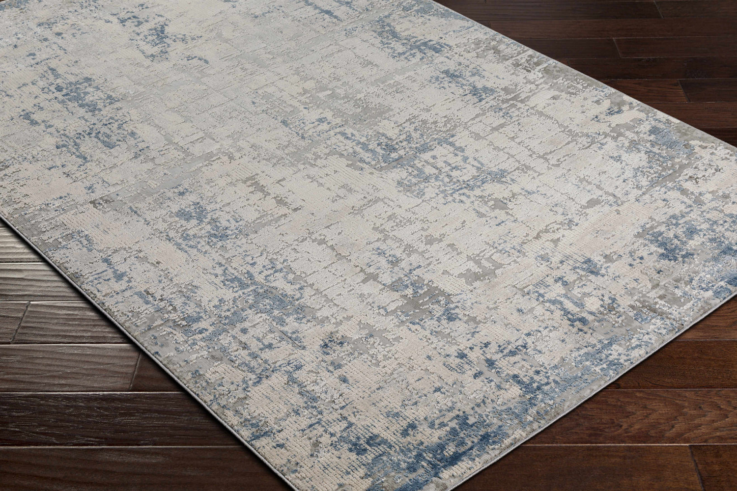 Close-up of the Saltair Textured Luxe Rug featuring a distressed blue, gray, and off-white contemporary pattern. Corner