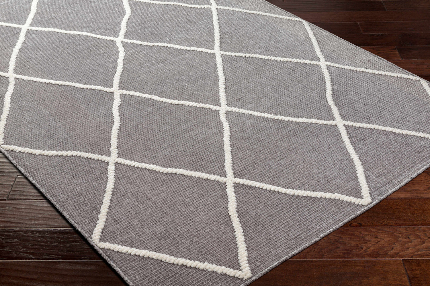 Close-up of the Amani Gray Washable Rug showing its geometric pattern and soft, textured white lines on a gray background. Corner