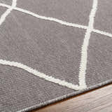 Close-up of Amani Gray Washable Rug. Features a dark gray base with a geometric white thatch pattern. Contemporary style. Texture