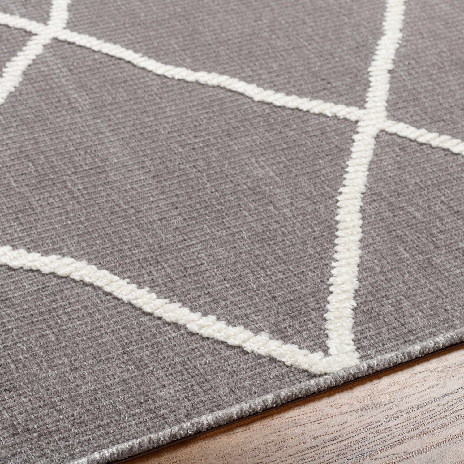 Close-up of Amani Gray Washable Rug. Features a dark gray base with a geometric white thatch pattern. Contemporary style. Texture