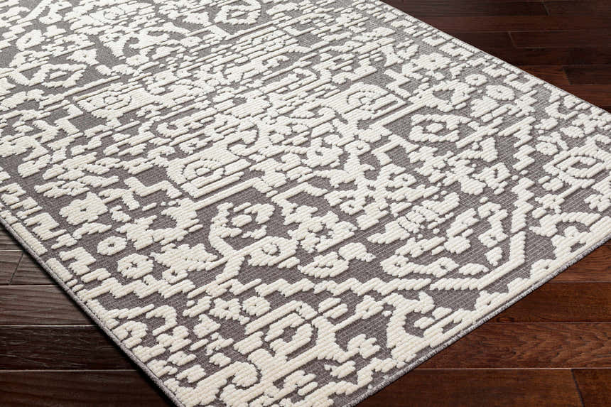 Close-up of the Beren Gray Washable Area Rug, showing a bone and gray traditional pattern with a slightly raised texture. Corner