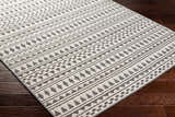 Close-up of the Cili Washable Area Rug in cloud gray. Features a geometric, tribal-inspired pattern. Machine woven texture. Corner