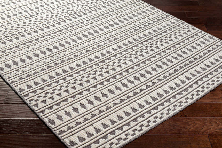 Close-up of the Cili Washable Area Rug in cloud gray. Features a geometric, tribal-inspired pattern. Machine woven texture. Corner