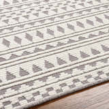 Close-up of the Cili Washable Area Rug in cloud gray and light gray with a geometric pattern. Machine woven texture. Texture