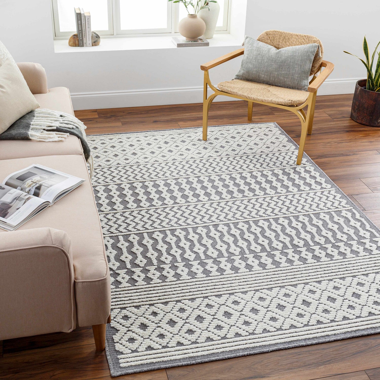 Living room scene with Drago Gray 3D Area Rug, bone and gray geometric pattern, styled with a sofa and woven chair. Roomscene-Rectangle