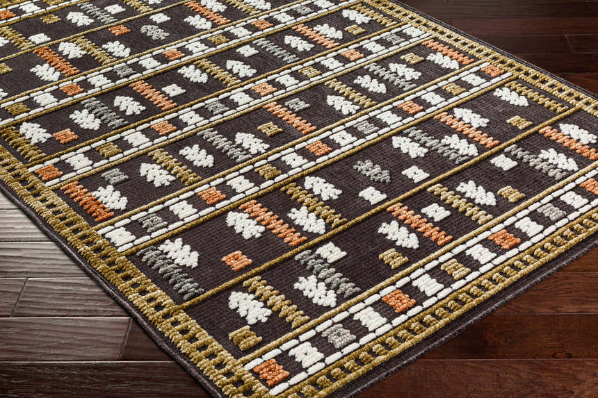 Close-up of Kade Washable Area Carpet. Dark beige rug with geometric Southwestern pattern in dusty sage, lambswool, and gray. Corner