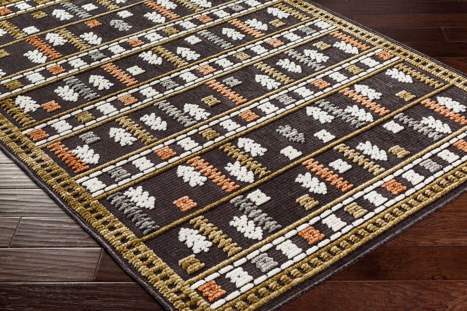 Close-up of Kade Washable Area Carpet. Dark beige rug with geometric Southwestern pattern in dusty sage, lambswool, and gray. Corner