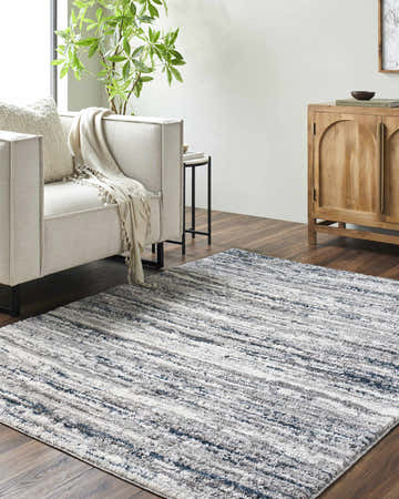 Living room scene with Skule Gray & Blue Area Rug, beige sofa, wood cabinet, and dark wood floors. Roomscene-Rectangle