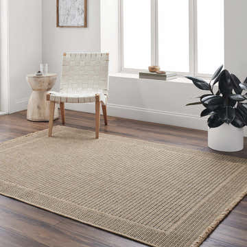 Bright room with oatmeal Giada Indoor Outdoor Rug, woven chair, side table, and plant. Roomscene-Rectangle