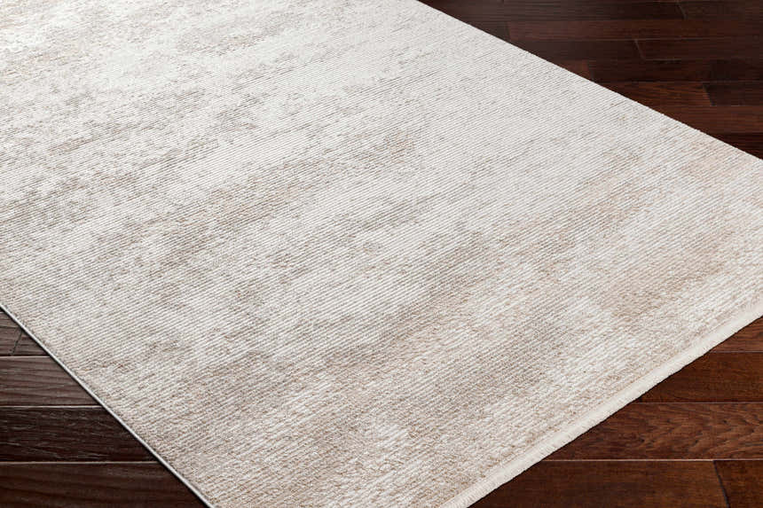 Close-up of the Ayah Area Rug in light gray and brown on a dark wood floor, showing its contemporary design. Corner