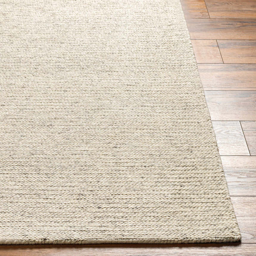 Close-up of the hand-woven Alyra Beige Solid Area Rug showing texture and color on hardwood floor. Front