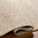 Close-up of the hand woven Alyra Tan Solid Area Rug showing texture and color variations of lambswool and taupe. Fold