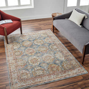 Living room scene with a Crescentia Blue & Beige Textured Rug, gray sofa, and brick red chair on dark wood floors. Roomscene-Rectangle