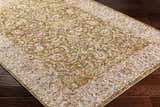 Close-up of the Dyan Green Textured Rug. Farmhouse style rug with olive, tan, red, and blue floral pattern. Corner