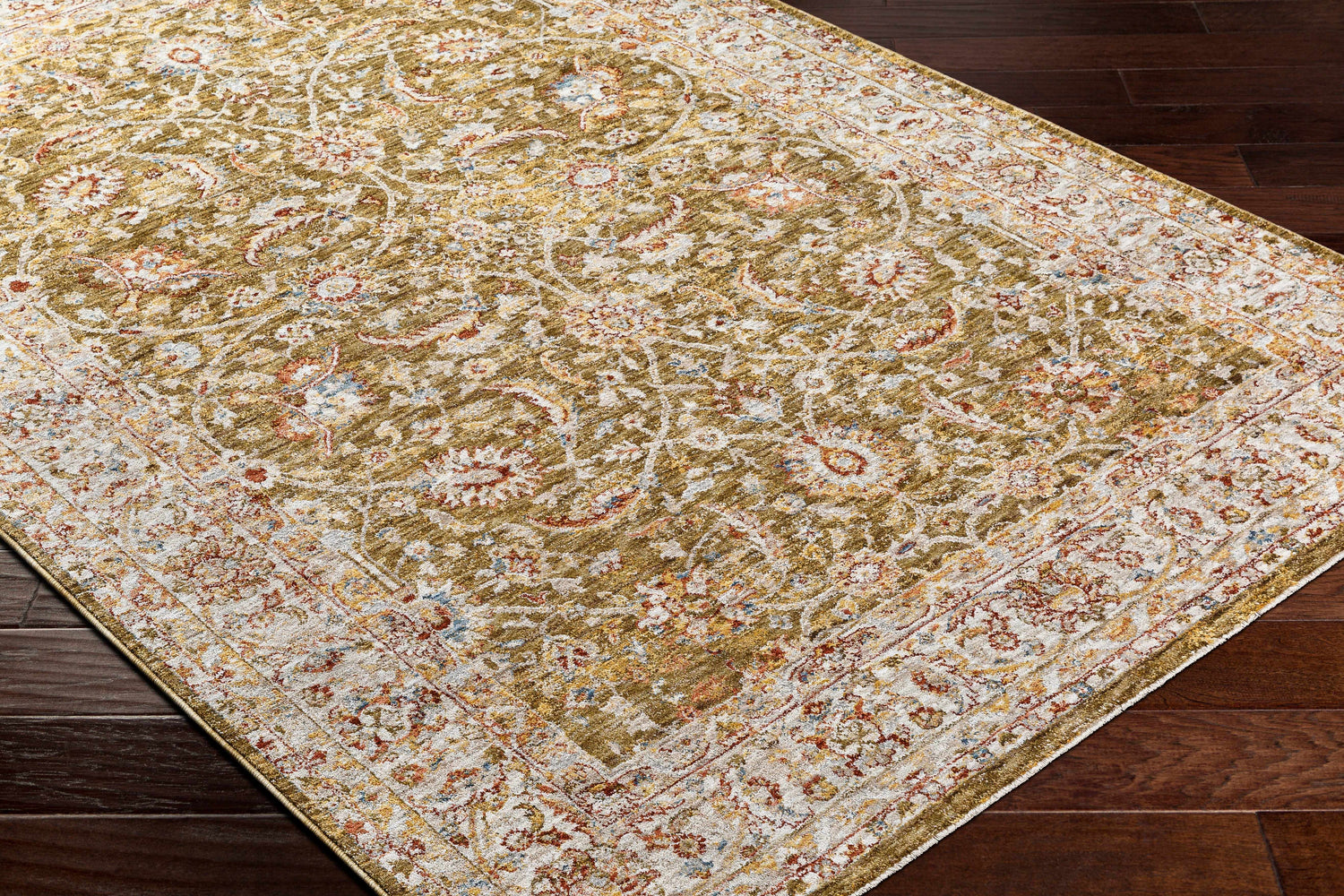 Close-up of the Dyan Green Textured Rug. Farmhouse style rug with olive, tan, red, and blue floral pattern. Corner