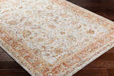 Close-up of the Dyan Cream Textured Rug with Fringes on dark wood floors. Features brick red, mustard, and blue floral pattern. Corner