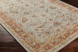 Close-up of the Dyan Cream Textured Rug. Features a traditional floral pattern with brick red, mustard, and blue accents. Corner