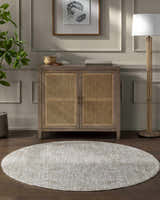Living room scene with light gray Katia area rug, wood cabinet, and floor lamp. Roomscene-Round