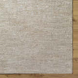 Close-up of the light gray Kyran Area Rug showing its subtle traditional pattern and soft, textured weave on wood floor. Corner